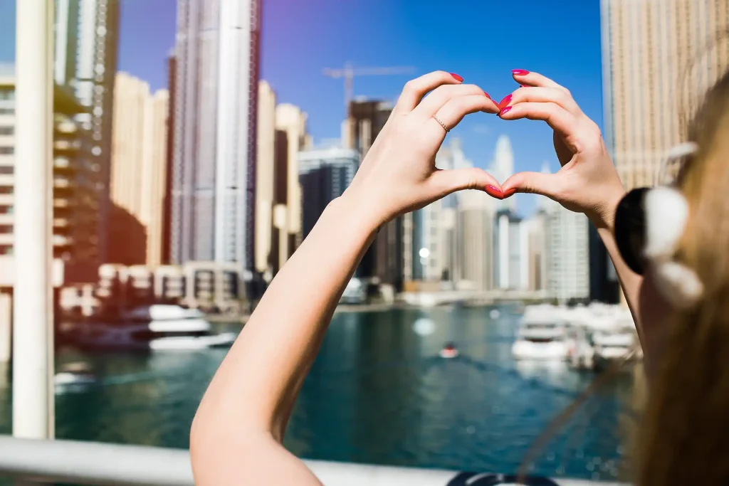 lady-with-red-nails-shows-heart-with-her-fingers-before-skyscrapers-dubai