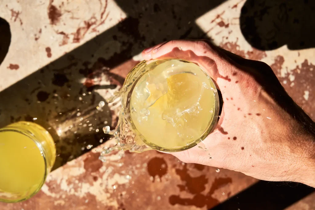 unrecognizable-man-s-hand-holding-glass-fresh-lemonade-top-view